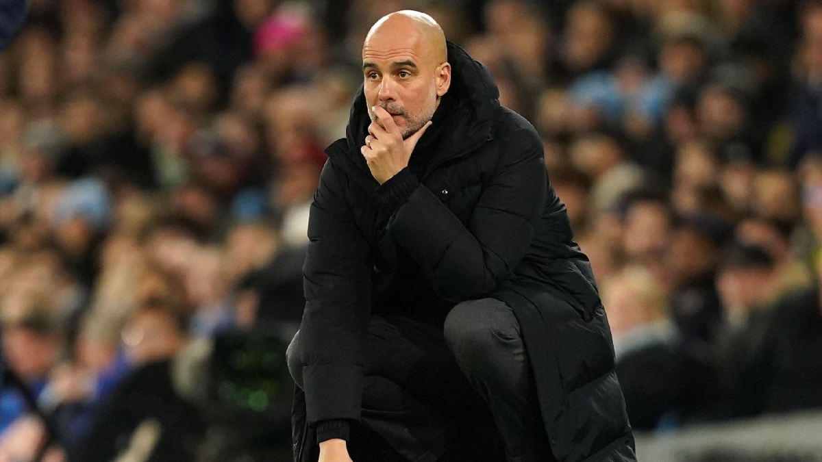 Pep Guardiola crouches on the touchline during Manchester Citys game against Brentford